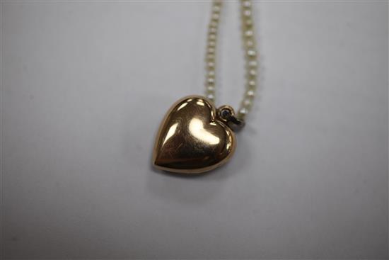 An early 20th century gold, ruby and split pearl set heart shaped pendant locket, pendant inc. bale 1in.